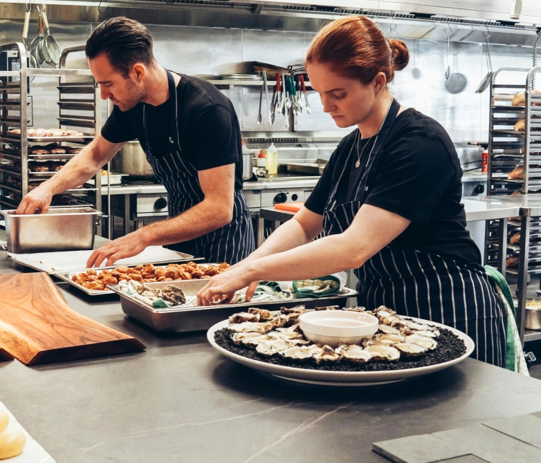 Two chefs preparing food in a kitchen.