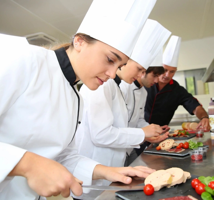 A group of chefs preparing food in a kitchen.